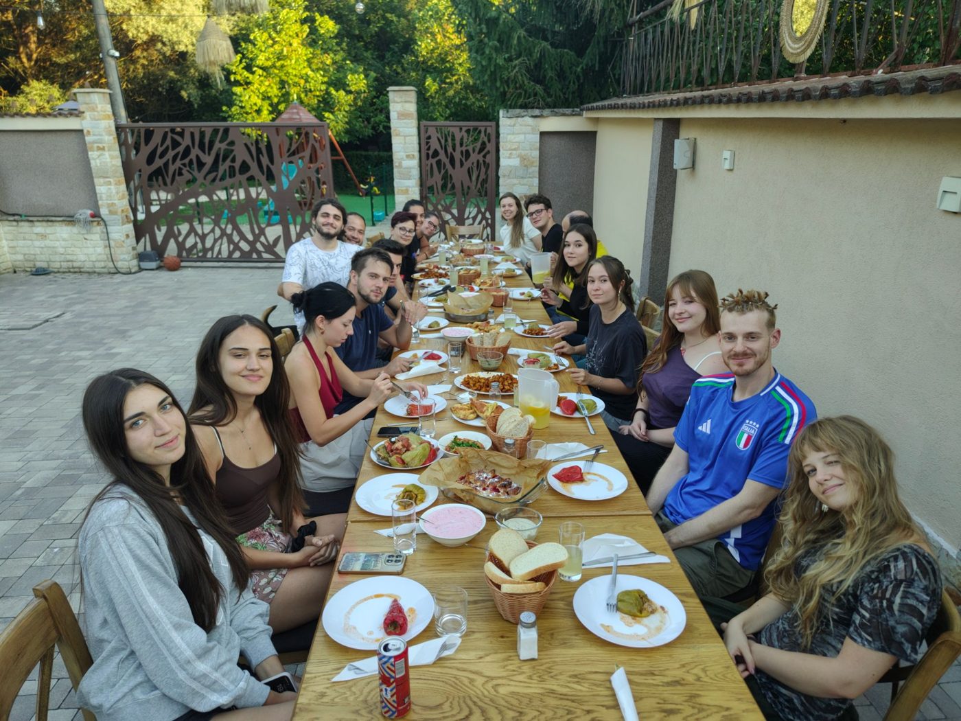 The whole group at a long table in the garden, sharing the dishes they cooked together