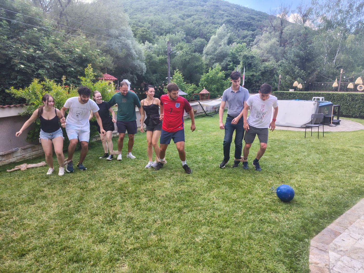 A line of participants tied together at the ankles, ready to chase the ball across the lawn