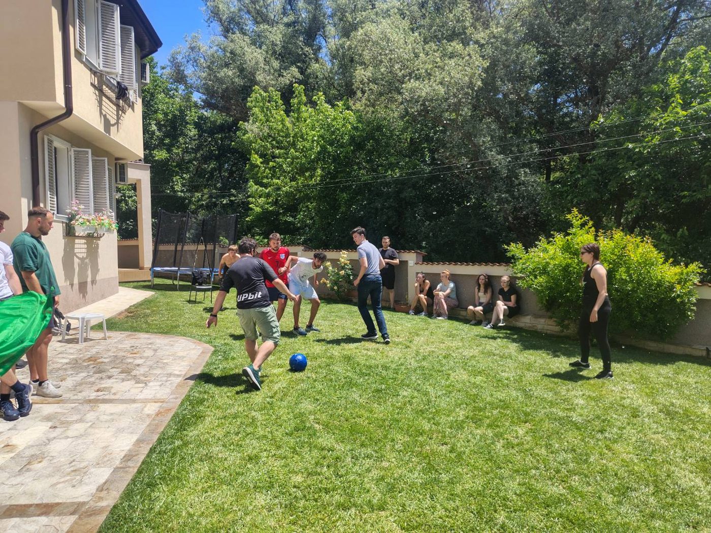 A match in the garden while the rest of the group watches from the wall