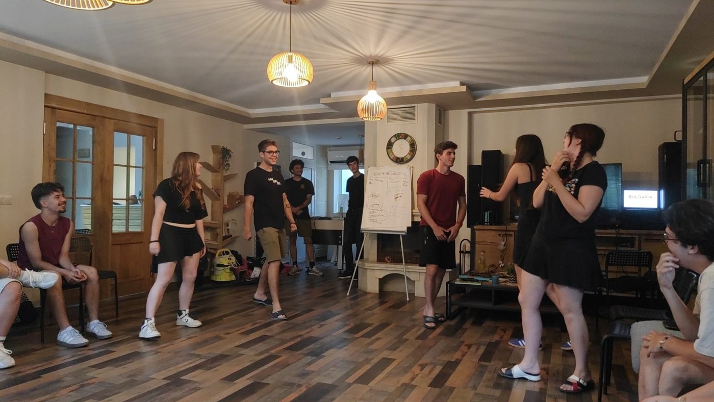 Participants in a circle during a warm-up game, the Theatre of the Oppressed flip chart behind them