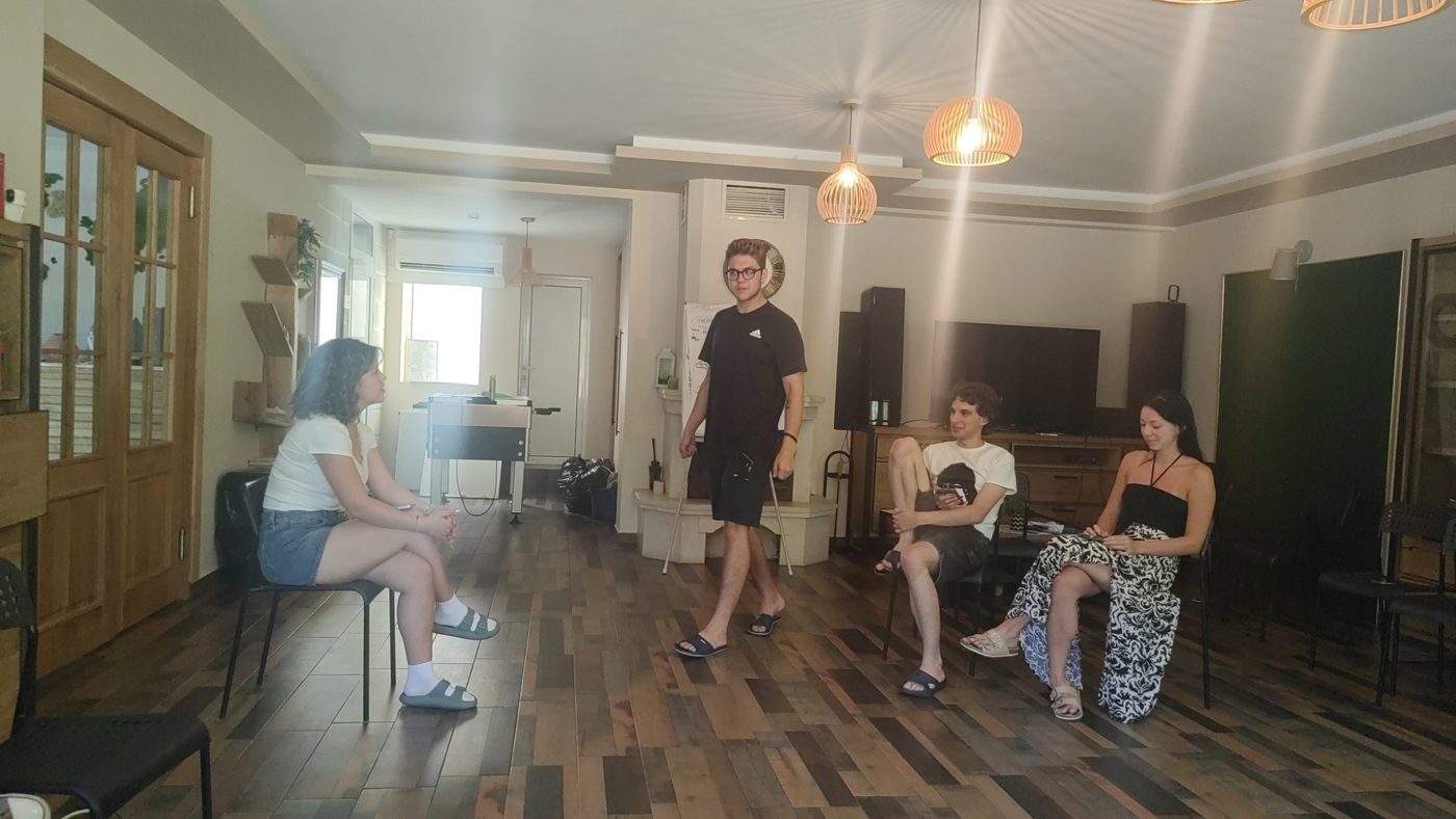 A participant walks through a scene while others watch from their chairs