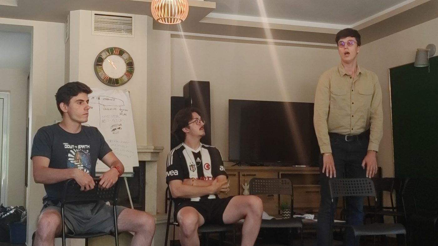A participant performs a monologue as two others look on
