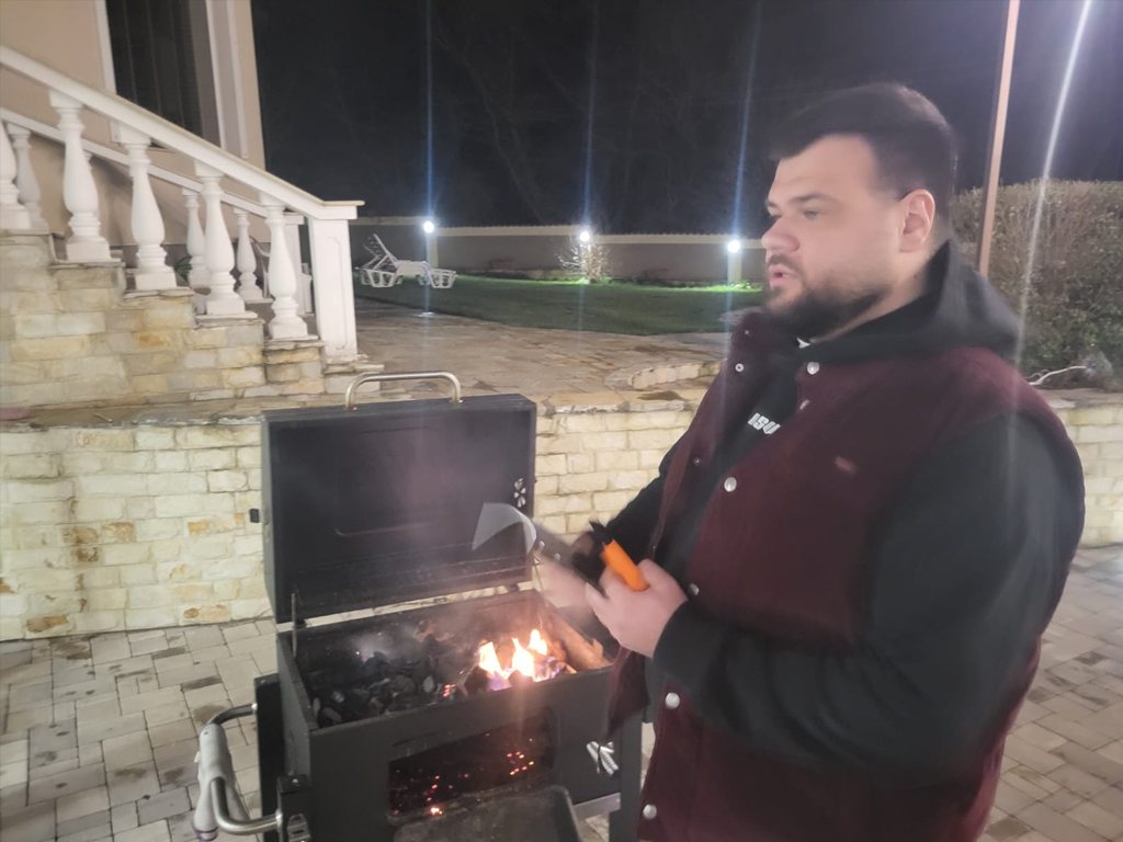 A participant grilling outdoors in the evening